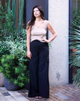 Full-length view of the taupe Kate Knit Top with black high-waist wide-leg trousers outdoors