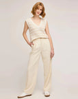 Full-length view of the natural striped Tanner knit vest with cream wide-leg pants and white sneakers