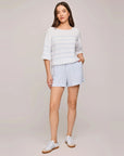 Full-length view of the Kerrigan sweater in Sky with blue striped shorts and white sneakers