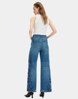 Model wearing Bayeas high rise wide leg jeans showing the medium blue wash and embroidered floral back detailing.