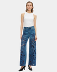 Model wearing Bayeas high rise wide leg jeans showing the medium blue wash and embroidered floral front detailing.