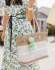 Model in a white floral wrap dress carrying the white and tan Coastal Net Tote on her arm