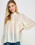 Front view of the Ivory Sheer Poet Blouse showing the pintucked yoke, ruffled collar and balloon sleeves, worn with jeans
