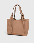 Montemare Sedona Tote in Latte shown from an angled view with braided handles, tassel detail, gold hardware and orange accent stitching.