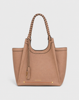 Montemare Sedona Tote in Latte shown from an angled view with braided handles, tassel detail, gold hardware and orange accent stitching.