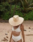 Model wearing the Nalu wide brim straw hat in natural styled for a relaxed summer look.
