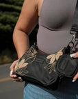 Close-up of the black Oceans End Kamalani bag worn crossbody with its clip-on pouch