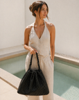 Model wearing the Sloane woven vegan leather hobo bag in black, showcasing slouchy shape and everyday shoulder carry.