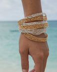 Handcrafted thin gold coral bangle bracelet with organic texture on model at beach