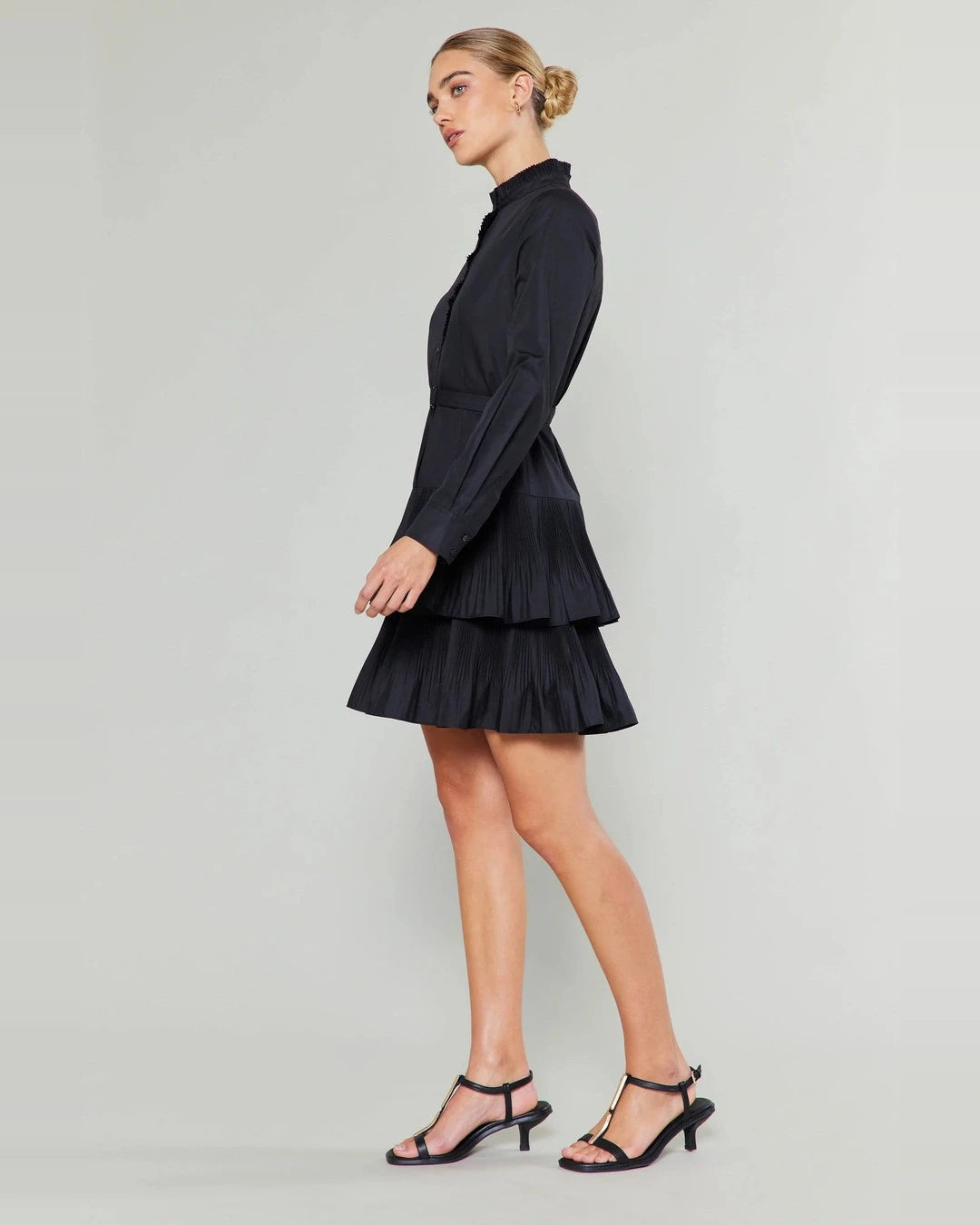 Full-length side view of the black Anberlin long sleeve mini dress with black strappy sandals