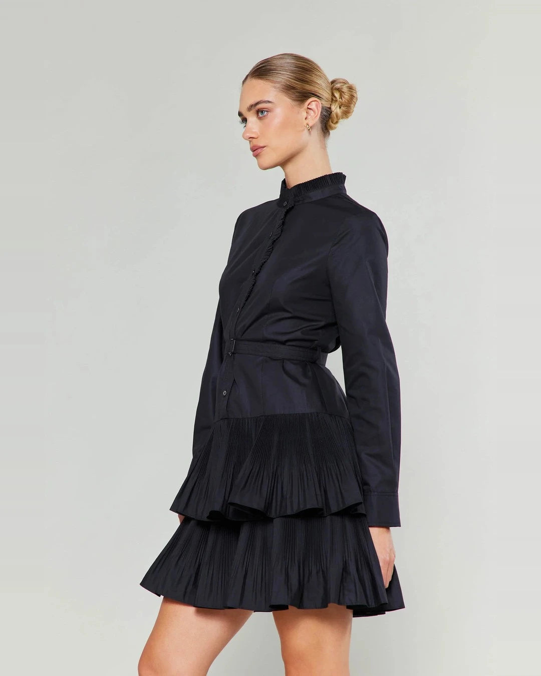 Side view of the black Anberlin Mini Dress showing the ruffle placket, belt and two pleated tiers