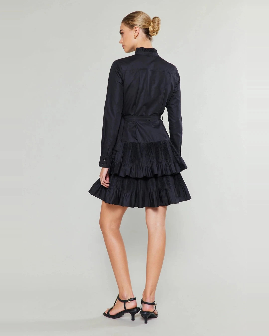 Back view of the black Anberlin Mini Dress with long sleeves, tie belt and tiered pleated skirt