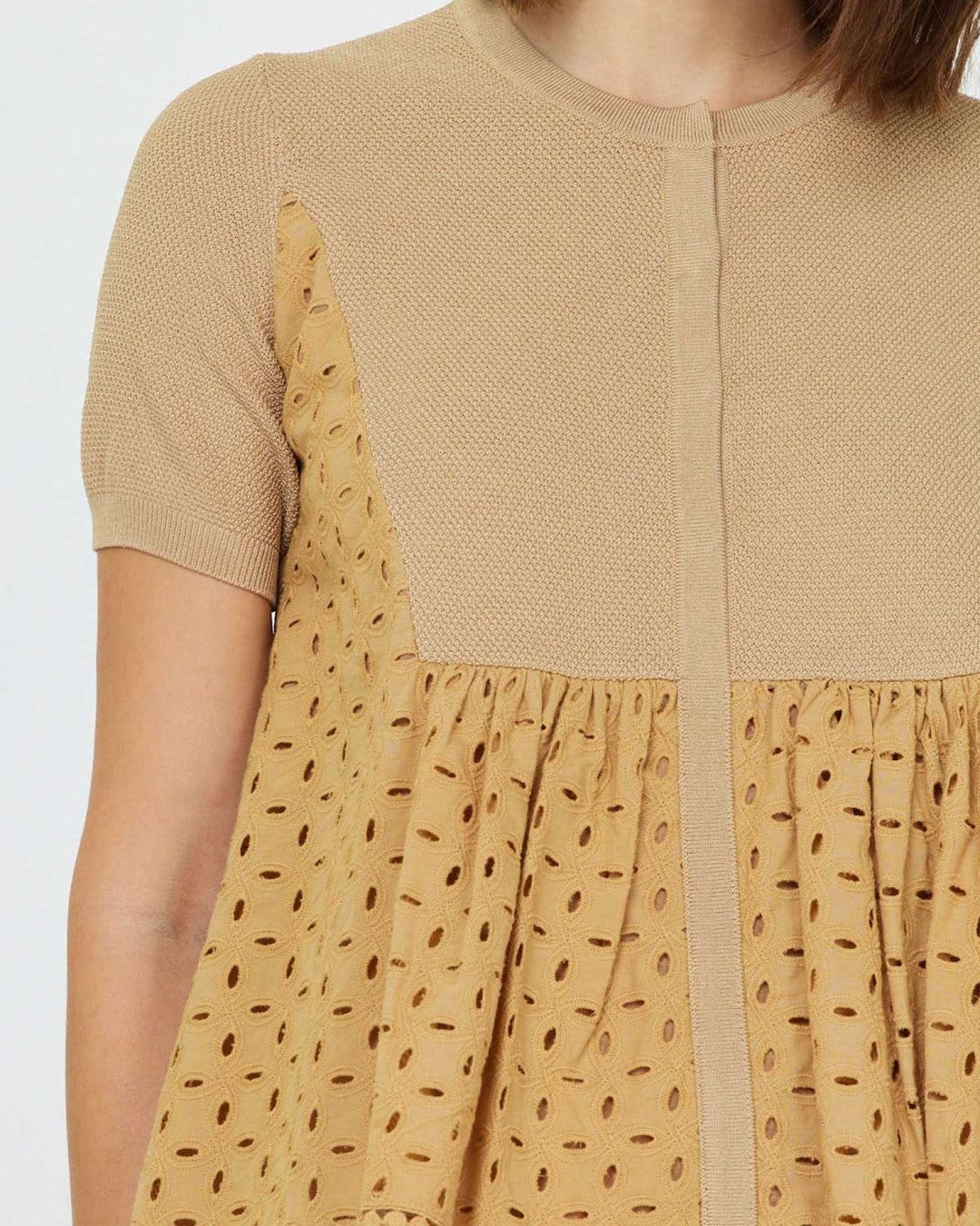 Close-up of the butterscotch eyelet fabric, center front placket and bobble trim at the hem