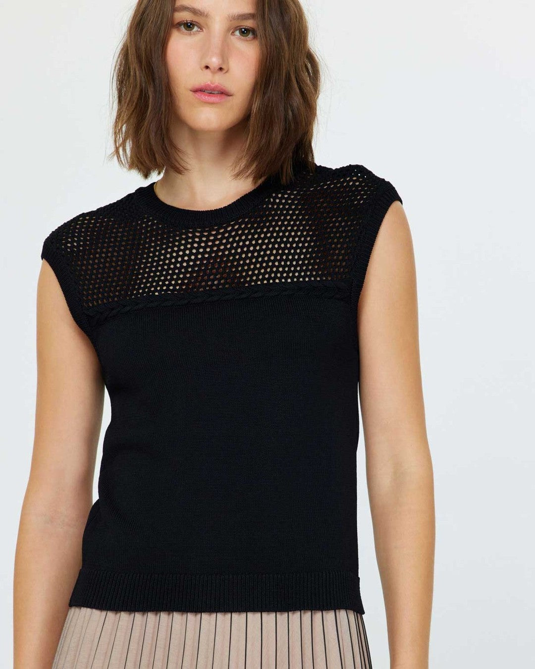 Current Air Stitched Sleeveless Sweater in black with open-stitch yoke, worn with a taupe pleated skirt