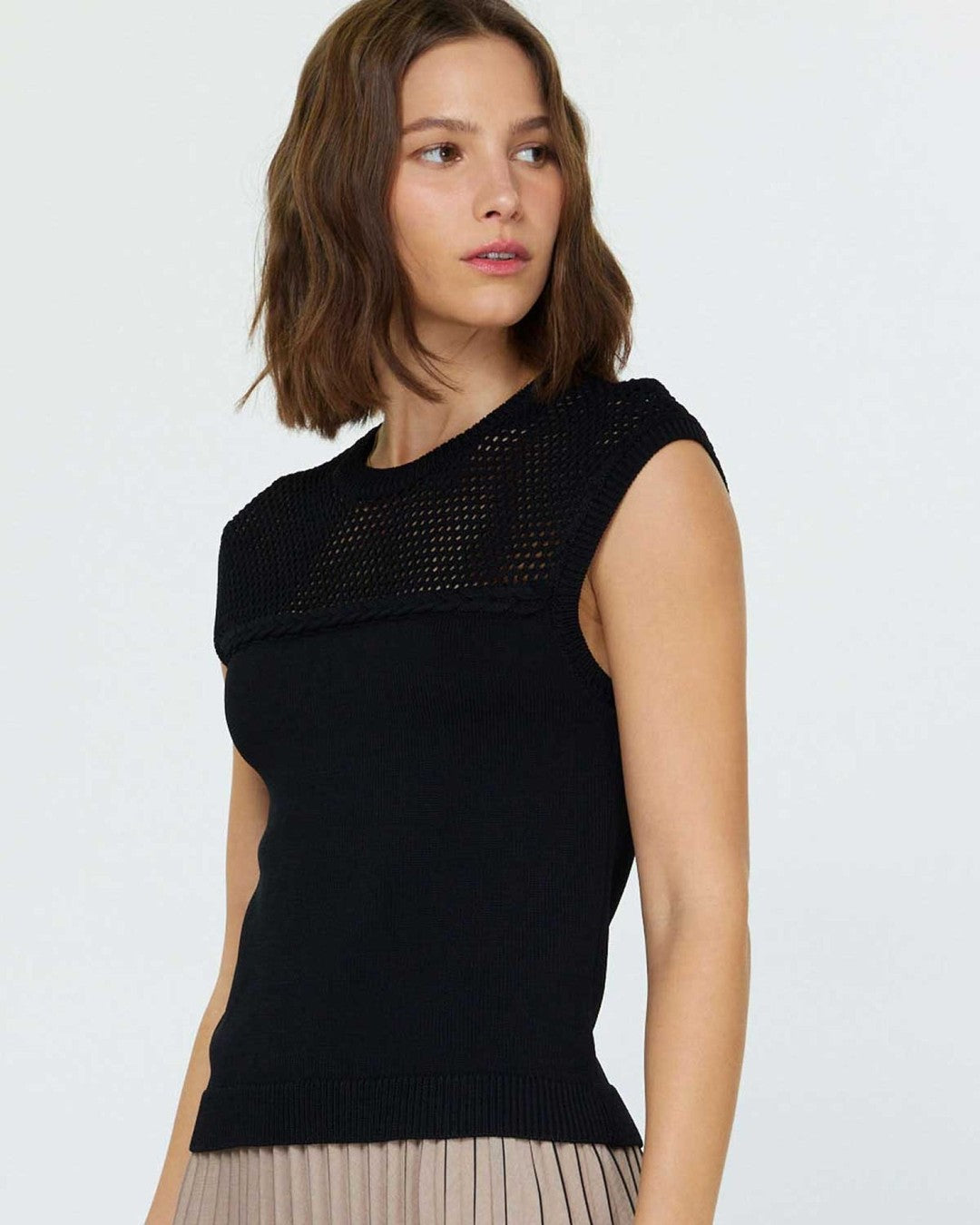 Side angle of the black Current Air sleeveless sweater with a pleated midi skirt