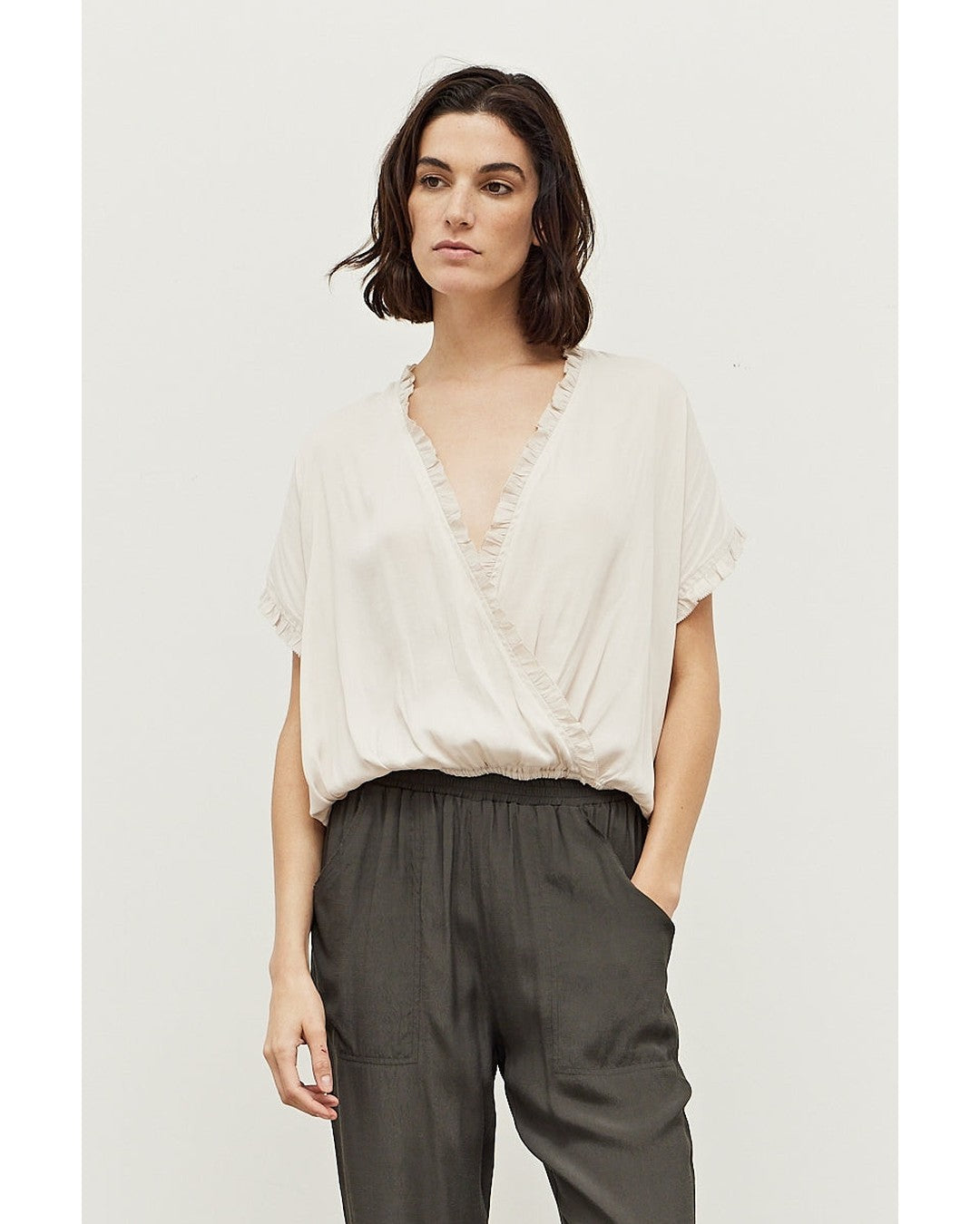 Ivory Sadie Satin Blouse with ruffle-trimmed surplice V-neck, front view with charcoal pull-on pants