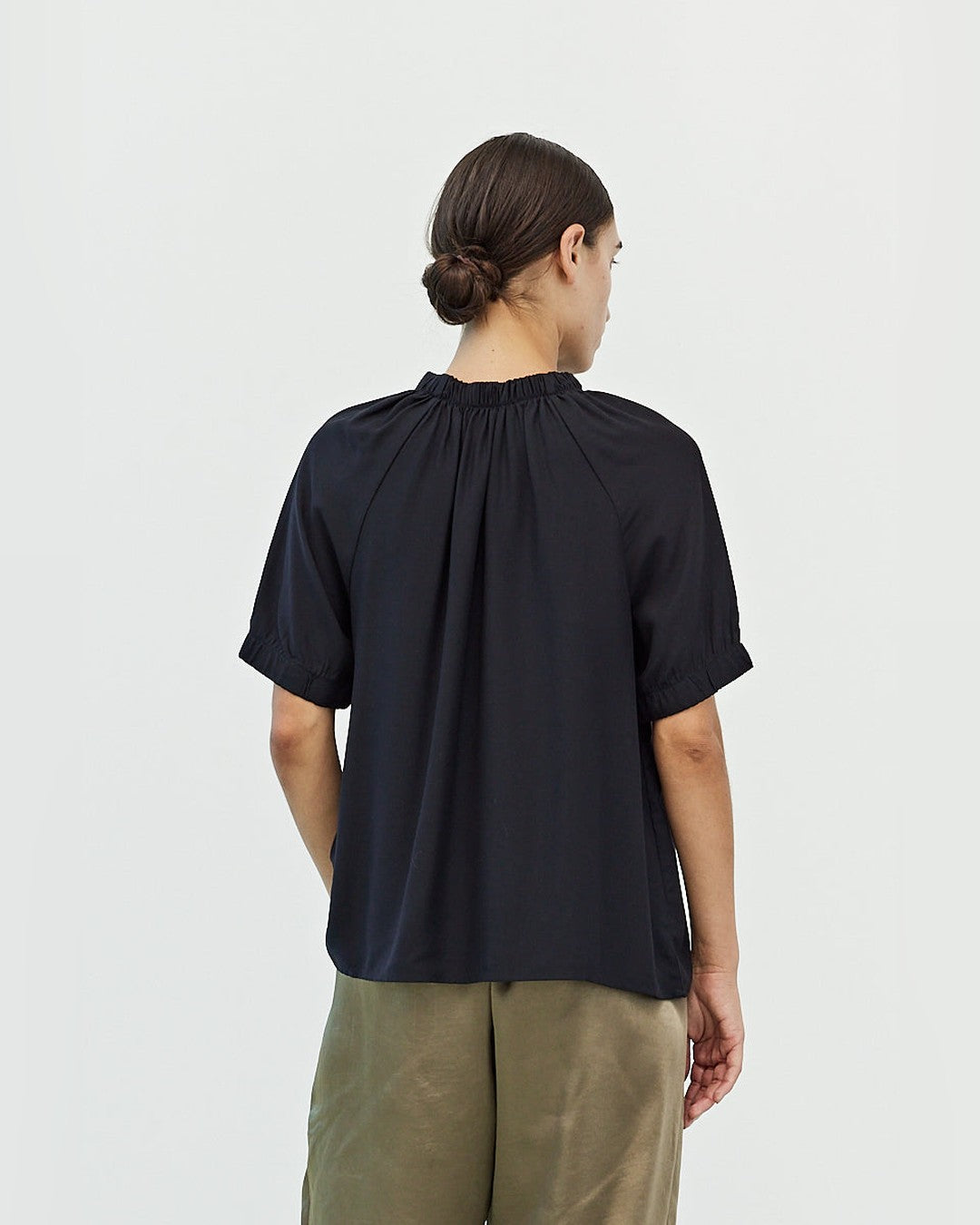 Back view of the black Mason Smocked Neck Blouse showing raglan seams and elastic puff sleeve cuffs