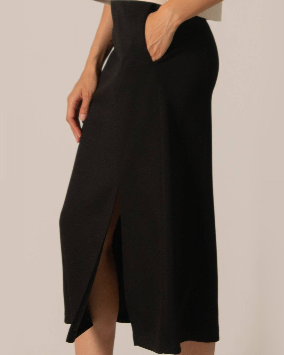 Close-up of the black Butter Modal midi skirt showing the slip pocket and slit