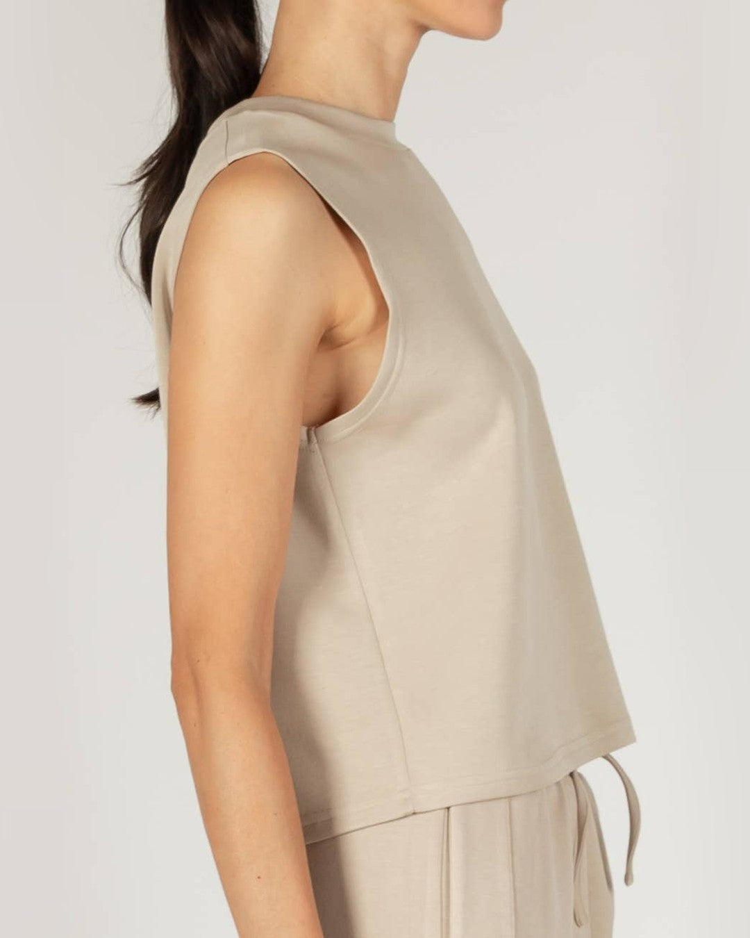 Close side view of the taupe P.CILL Birdie tank showing the cut-in armhole and straight hem
