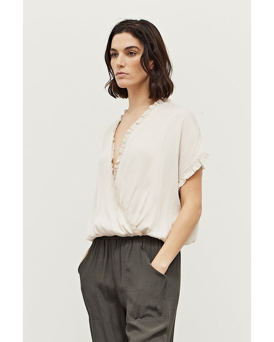 Three-quarter view of the ivory Sadie Satin Blouse showing ruffled cap sleeves and banded hem