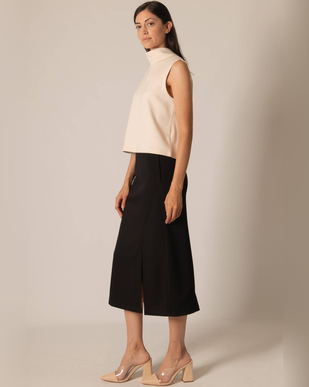 Side view of the black Butter Modal midi skirt with an ivory top and clear heeled mules