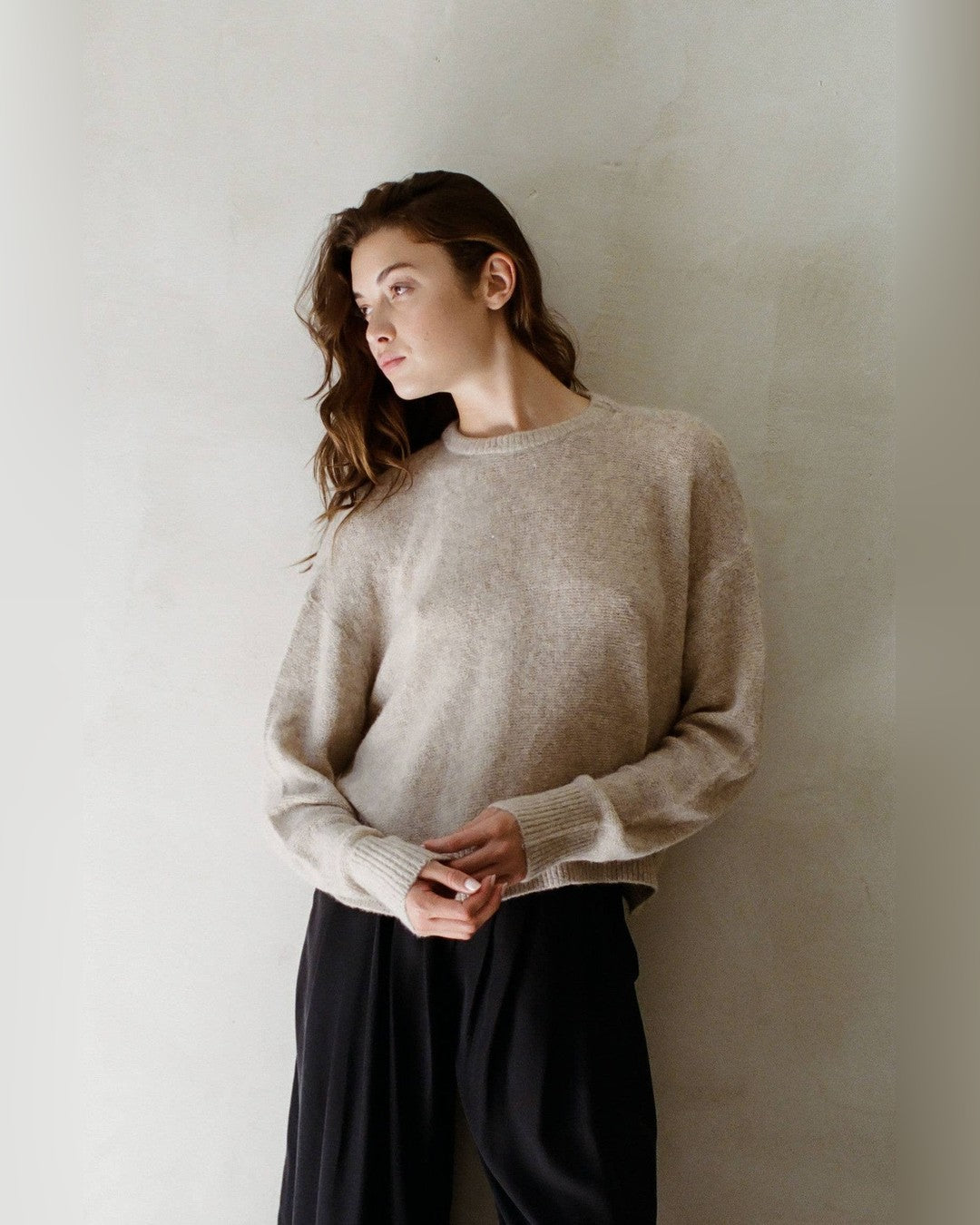 Beige Evie Pullover Sweater with crew neck and dropped shoulders, worn with black wide-leg trousers