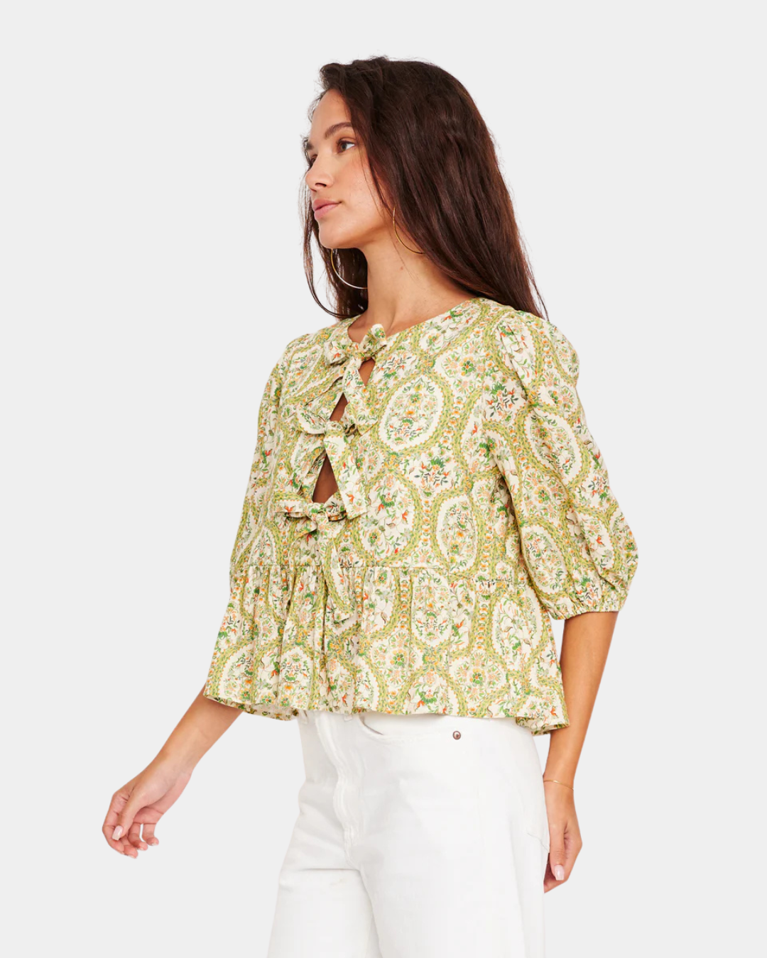 Close view of D.RA Ros floral blouse featuring front tie bows, subtle cutout detail, and three-quarter puff sleeves.