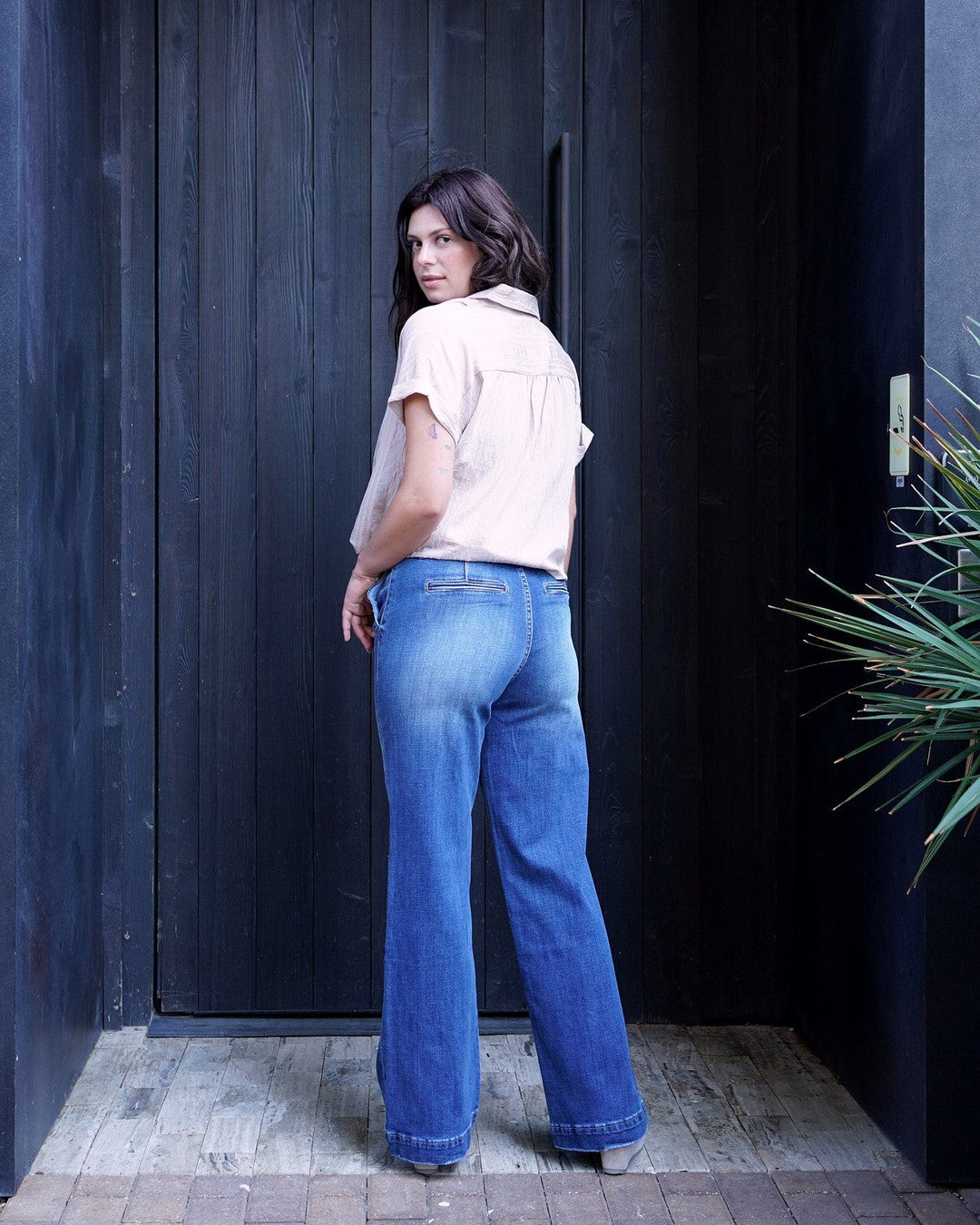 Back view of KanCan medium-wash denim trousers showing the back pockets