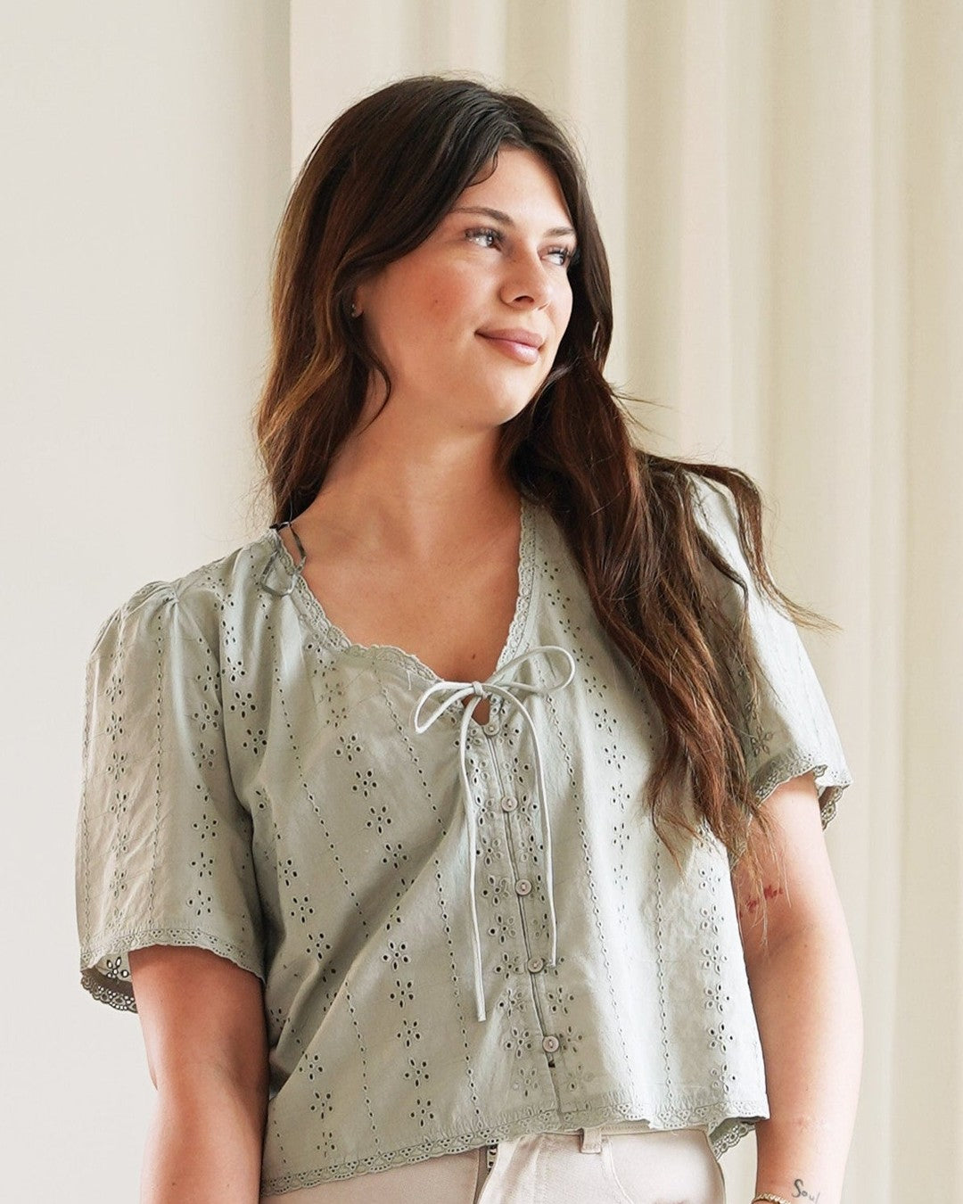 Gentle Fawn Jessa eyelet blouse in sage green with tie V-neck, worn with light jeans