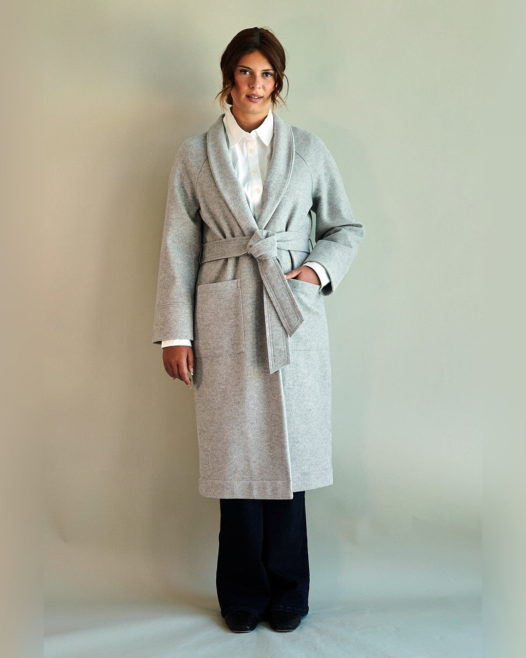 Light heather grey SoHo Belted Overcoat tied at the waist over a white shirt and navy trousers, front view