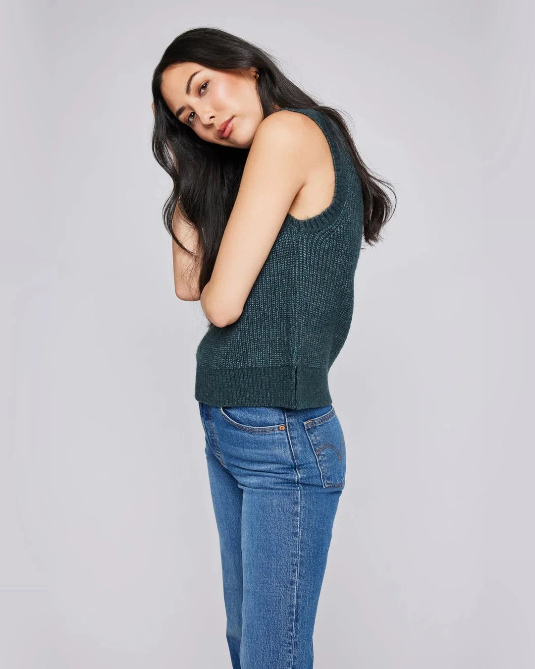 Side view of the forest green Peyton rib-knit sweater vest with blue jeans