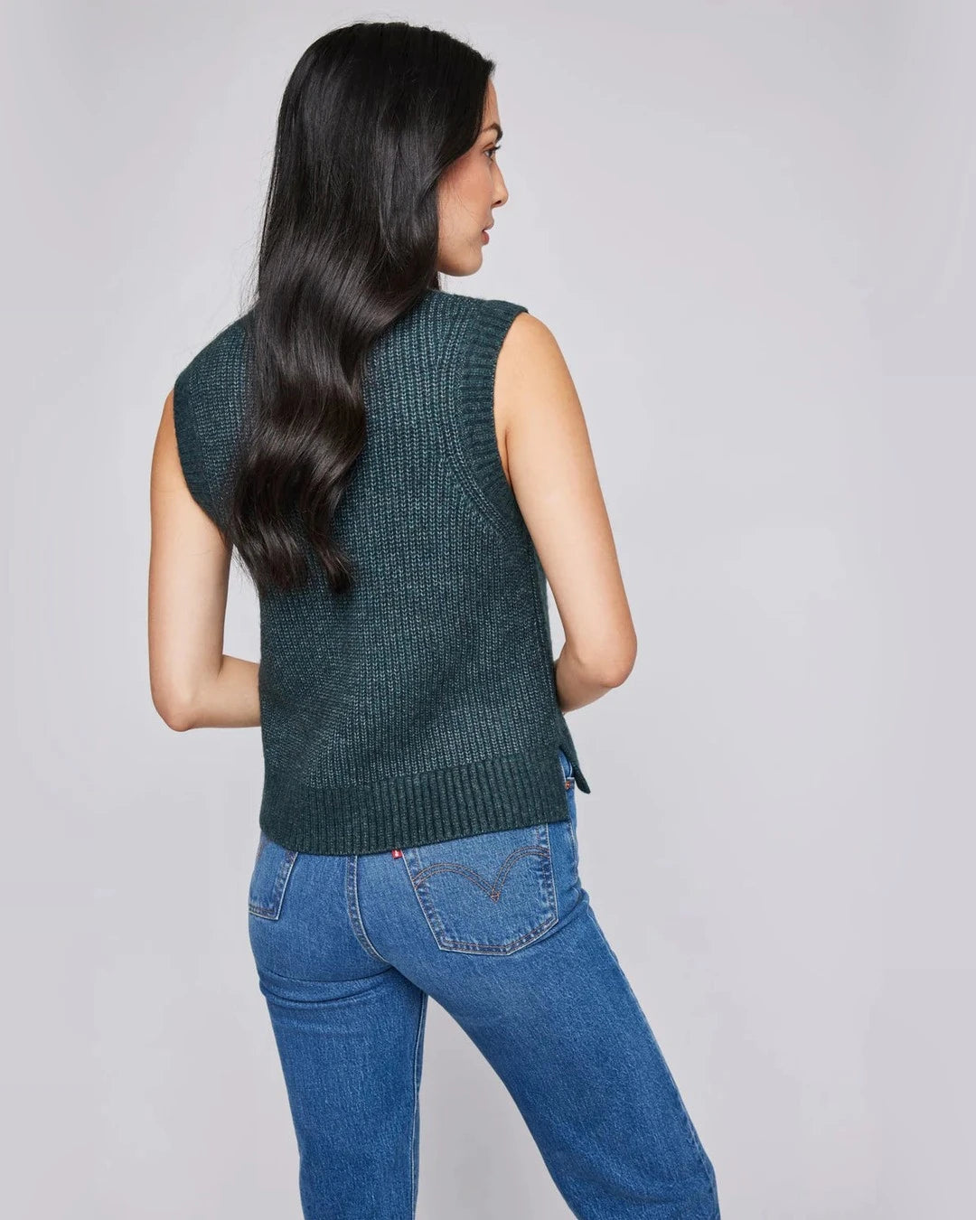 Back view of the forest green Peyton sweater vest showing the ribbed hem and side slit