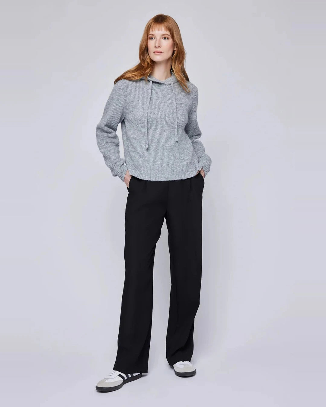 Full-length view of the heather grey Alanis hooded sweater with black wide-leg trousers and white sneakers