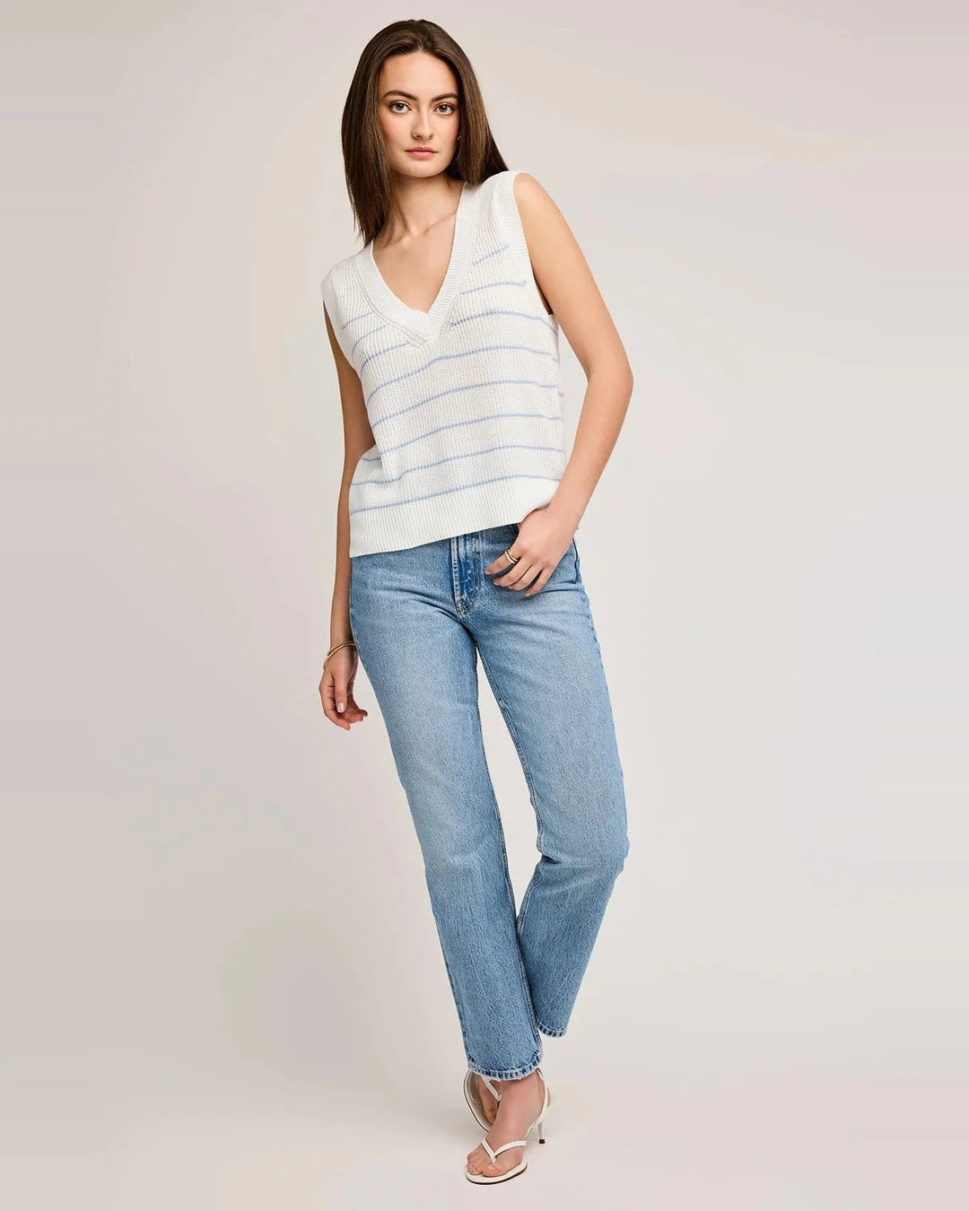 Full-length view of the blue striped Tanner knit vest with straight-leg jeans and white sandals