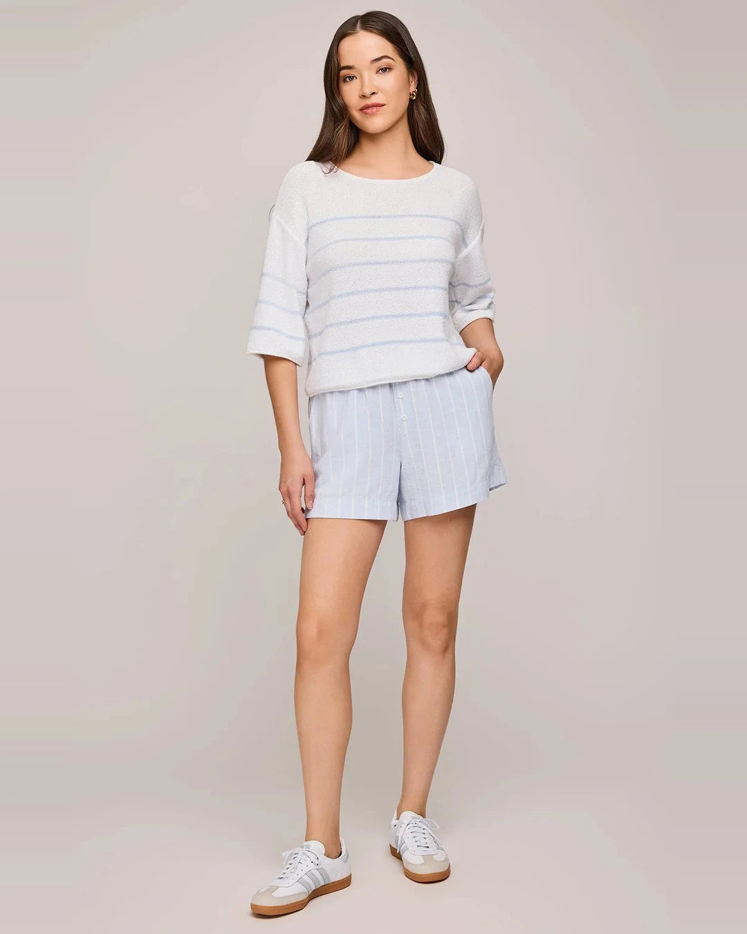 Full-length view of the Kerrigan sweater in Sky with blue striped shorts and white sneakers