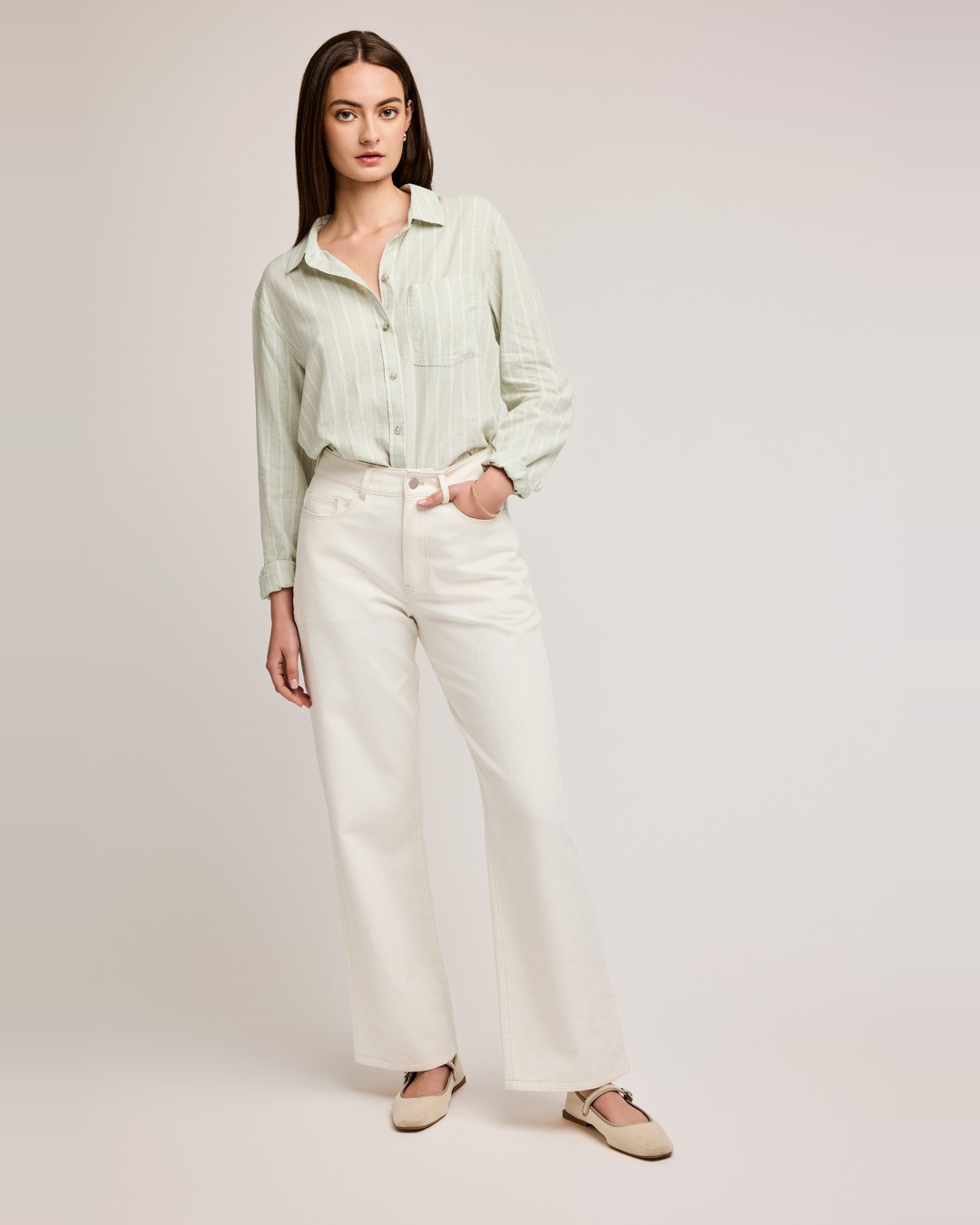 Full-length view of the mint stripe Dominique linen shirt with white wide-leg jeans and cream flats