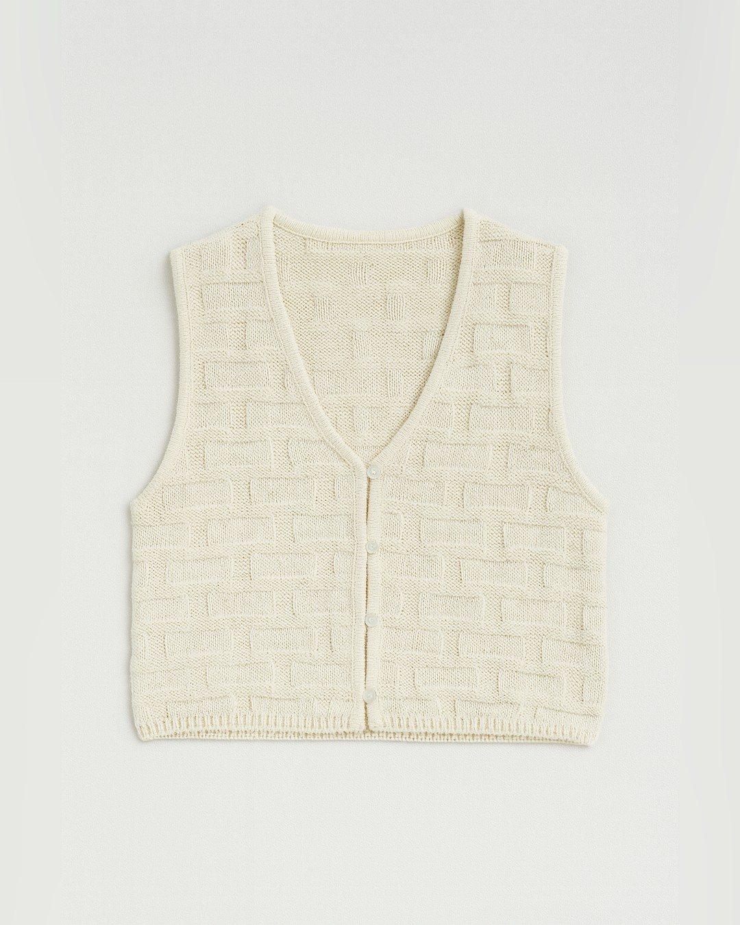 Flat lay of the cream Monroe Button-Front Sweater Vest with basketweave texture and button front