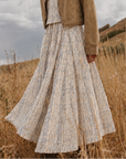 Model wearing the Azure Horizon Midi Skirt in a blue and ivory print with a tan jacket.