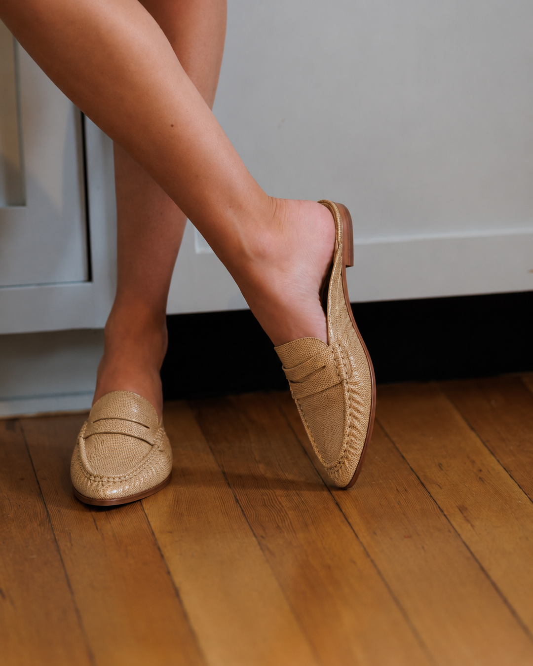Model wearing Dolce Vita Betzy crème embossed suede loafers on a wood floor
