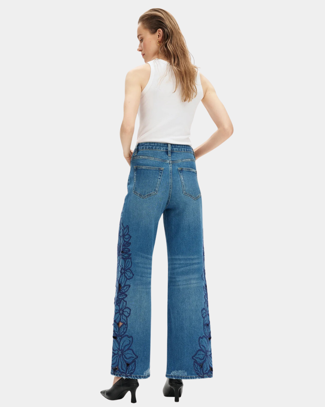 Model wearing Bayeas high rise wide leg jeans showing the medium blue wash and embroidered floral back detailing.
