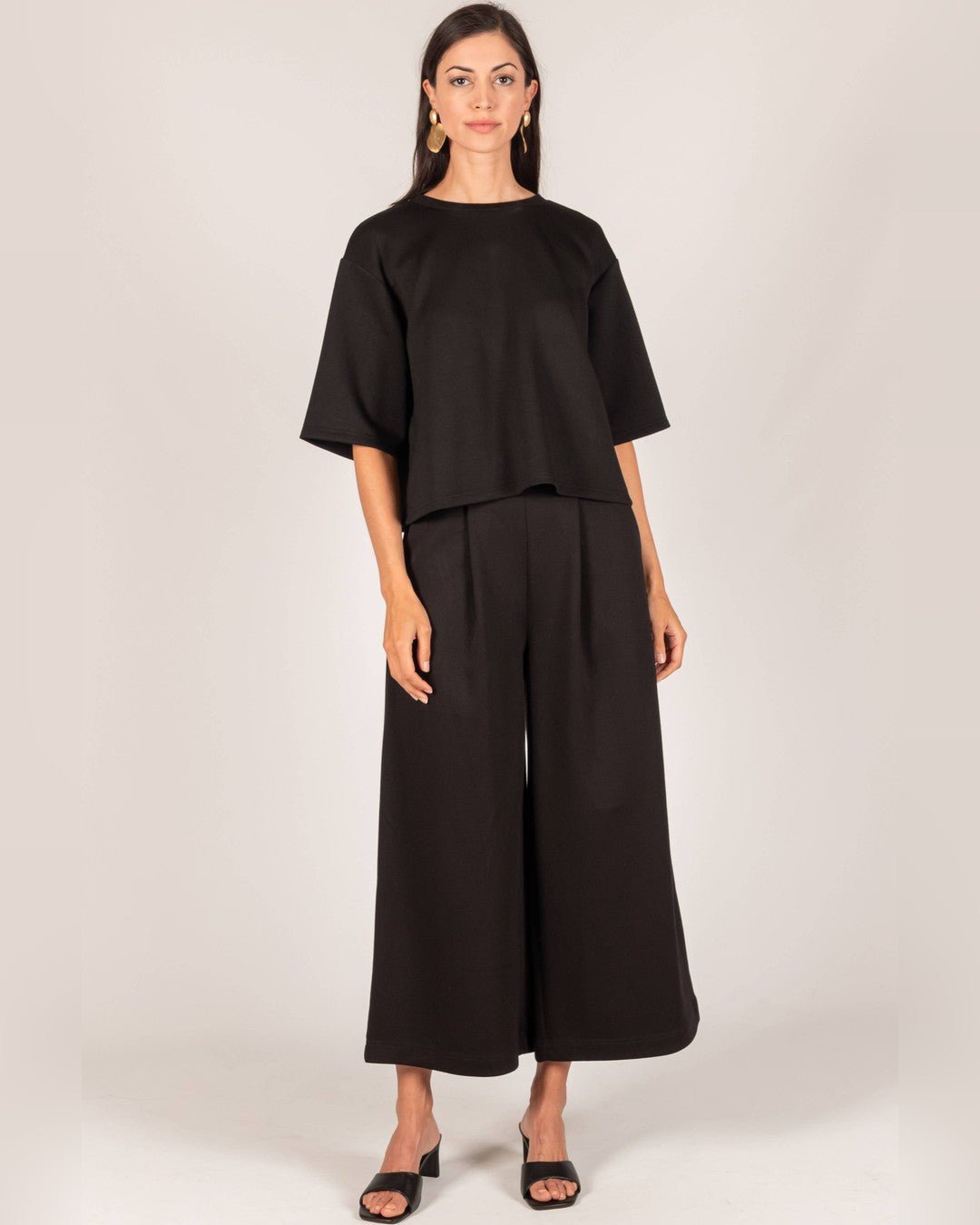 Front view of the black Hazel Overlap Back Top worn over high-waist black wide-leg pants