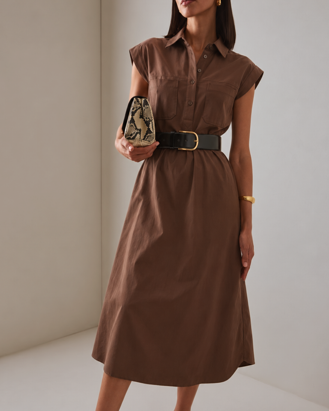 Model wearing the Modern Icon Shift Dress in Chocolate with a black belt and snakeskin clutch, front view