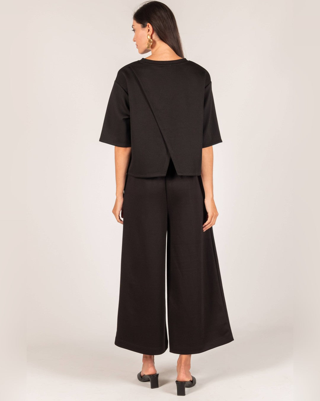 Back view of the black P.CILL Hazel Overlap Back Top with split back and wide-leg pants