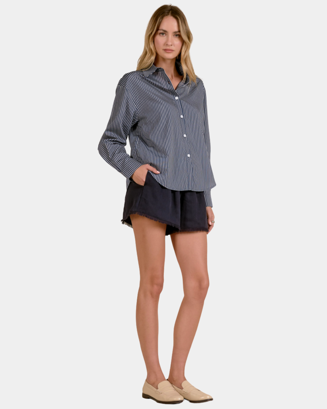 Model wearing the Elan Corey striped button down shirt in Blue Stripe with a relaxed fit and dark shorts.