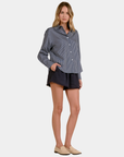 Model wearing the Elan Corey striped button down shirt in Blue Stripe with a relaxed fit and dark shorts.
