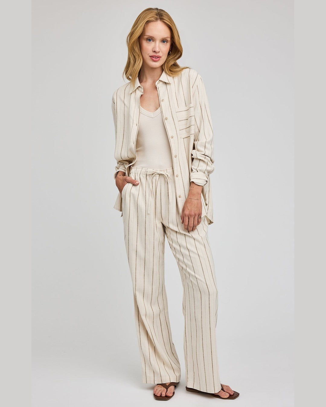 Model in Gentle Fawn Finley drawstring linen pants and matching Portia shirt in a cream and brown stripe
