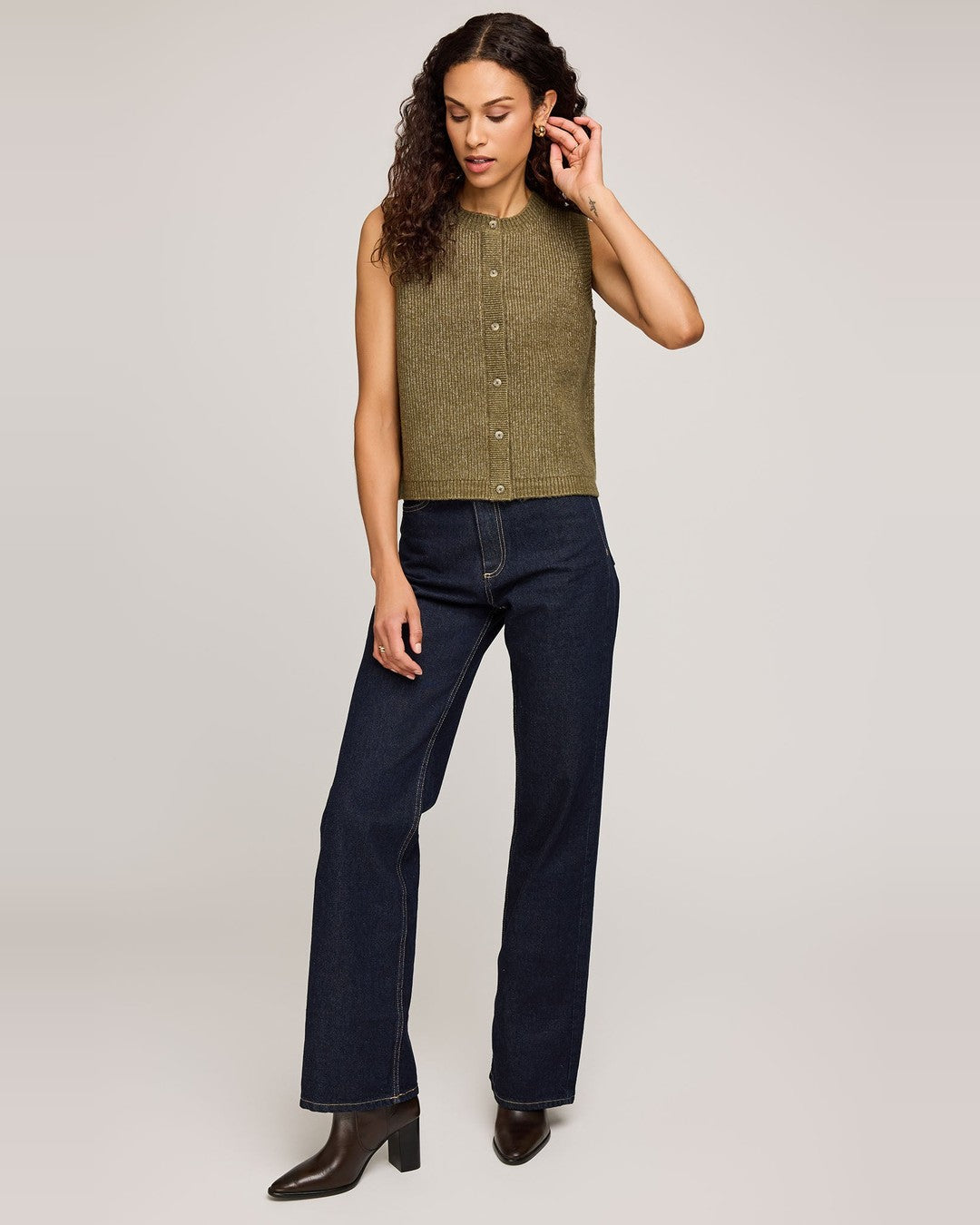 Full-length view of the olive Winnie button-front vest with dark wide-leg jeans and brown heeled boots