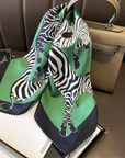 Green zebra print silk scarf tied on handbag as accessory