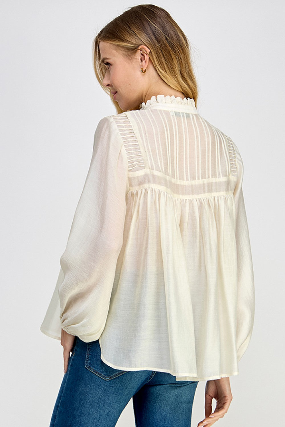 Side view of ivory sheer long sleeve blouse with flowy silhouette