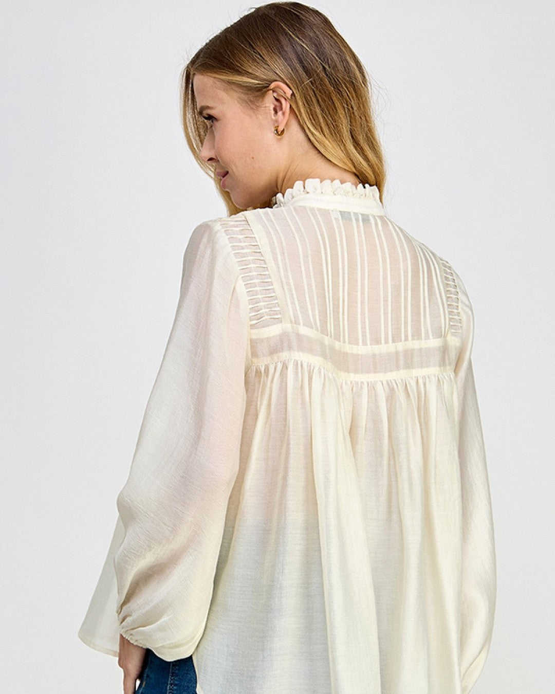 Side view of ivory sheer long sleeve blouse with flowy silhouette